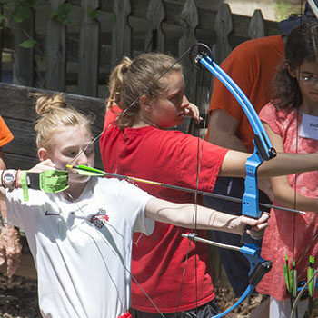 Two young women aiming arrows at summer archery at IWLA-R